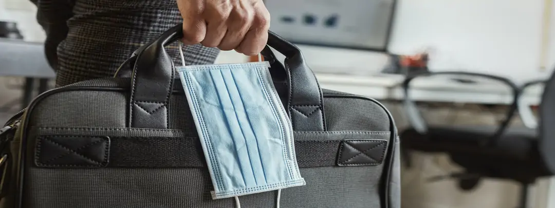 Viajero de negocios con maletín ordenador y mascarilla